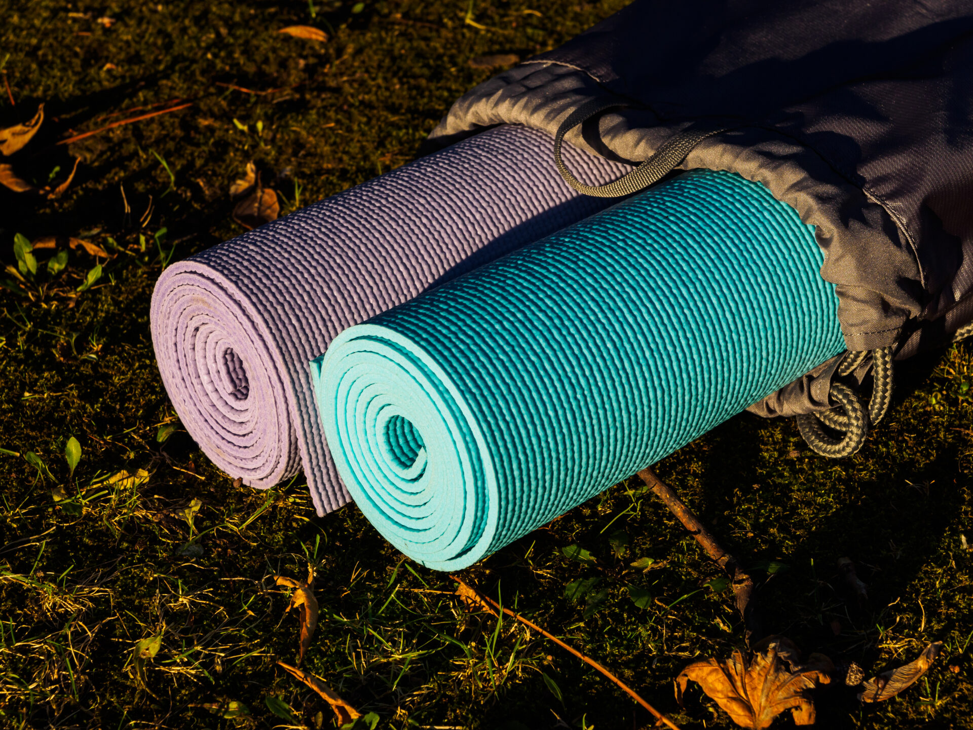 Yoga mats in grey cover on grass. The concept of a healthy lifestyle. Yoga or physical education classes in the fresh air, in the Park or in nature. Yoga for two, pair yoga Yogamatten in grauer Hülle auf Gras. Das Konzept eines gesunden Lebensstils. Yoga- oder Sportunterricht an der frischen Luft, im Park oder in der Natur. Yoga zu zweit, Partner-Yoga.